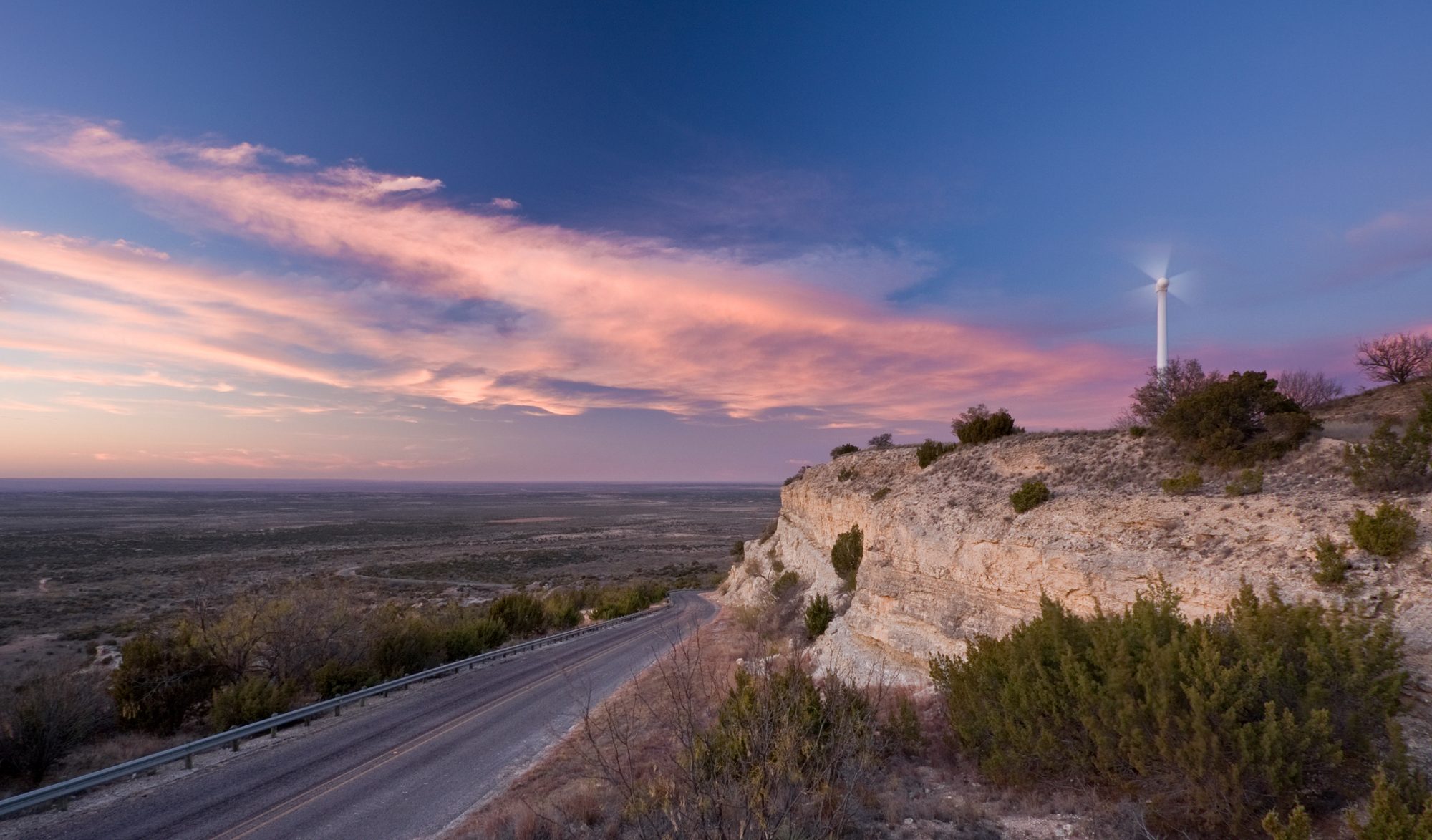 Wind turbine above a ridge road at dusk on the Central Asian steppe
